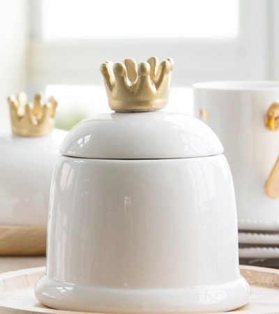 Белая керамическая емкость для хранения с золотой короной на крышке.